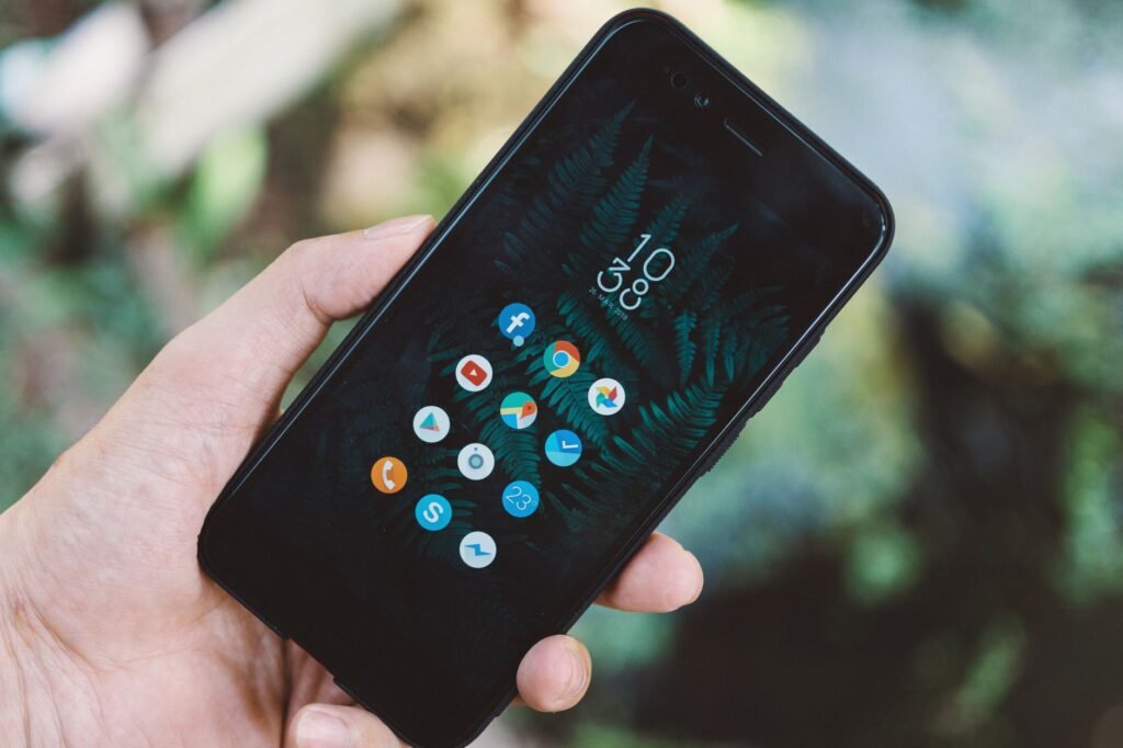 Close-up of a hand holding a smartphone with app icons on screen