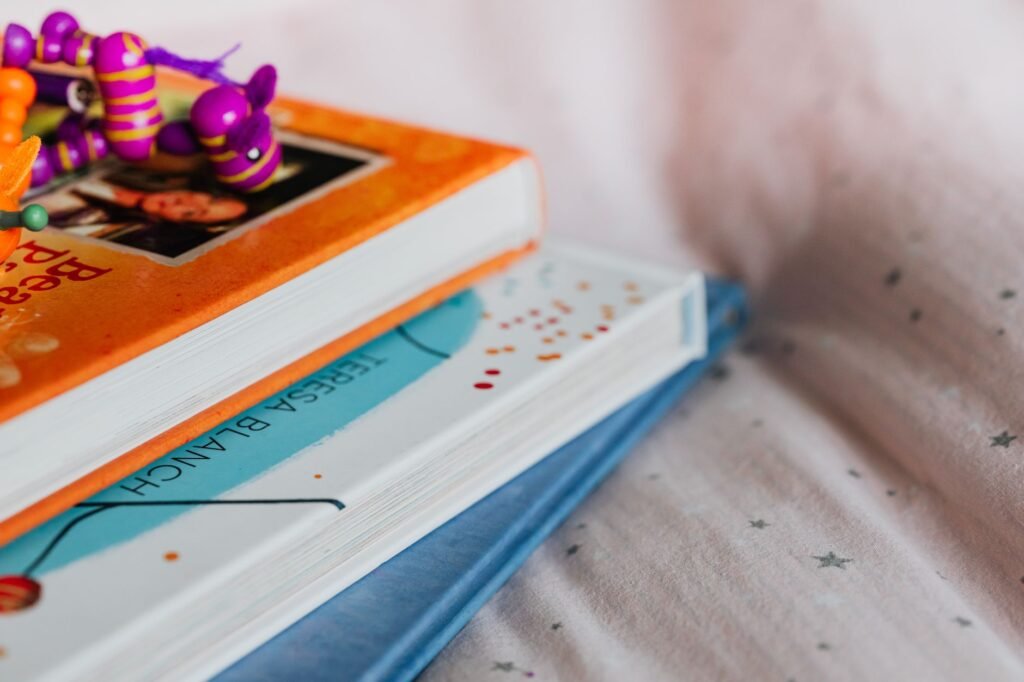 A stack of colorful children's picture books with a small toy on top