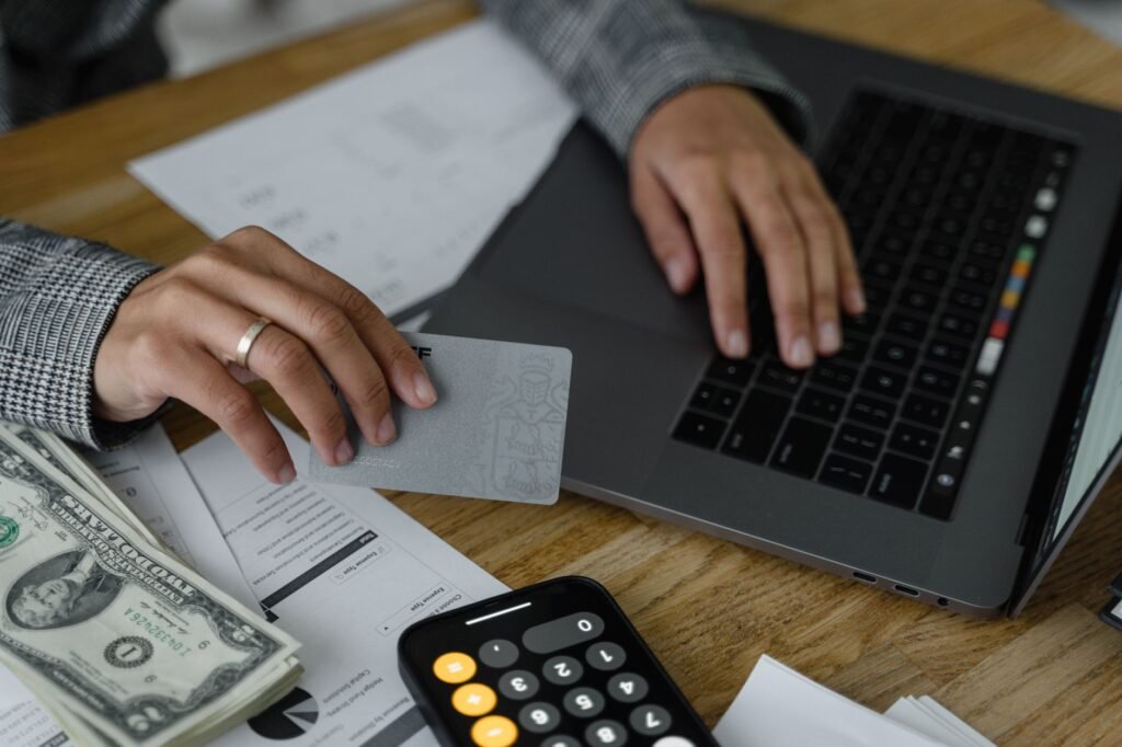 Close-up of a person holding a credit card while using a laptop
