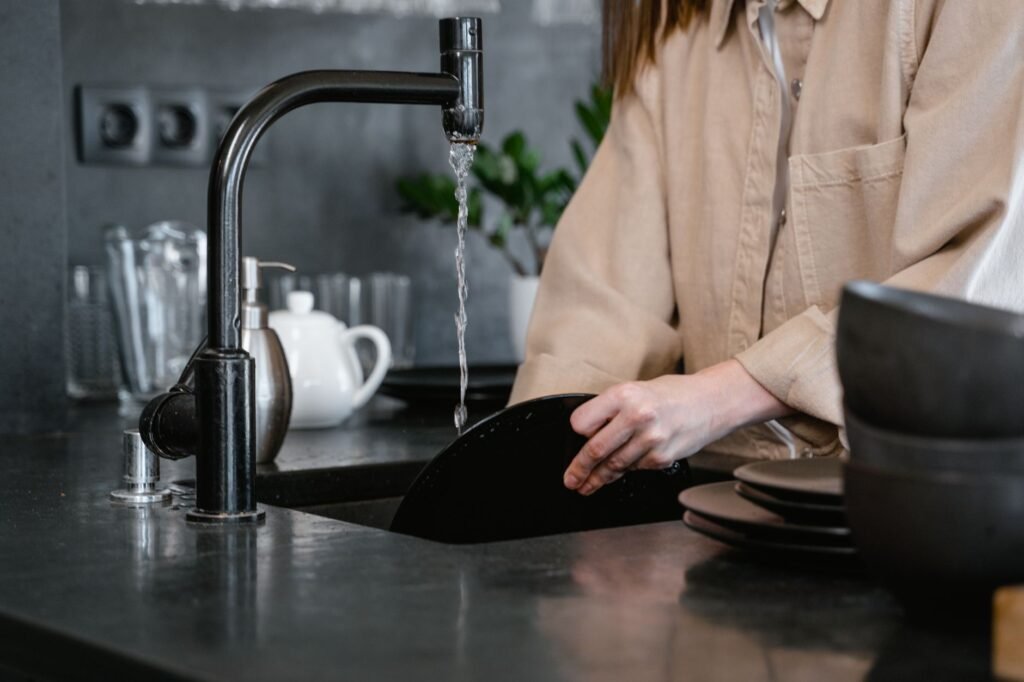 Washing dishes at a kitchen sink, where food scraps reach the garbage disposal