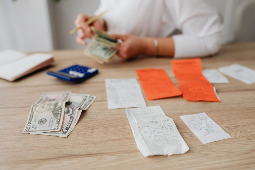 A person using a calculator and cash at a table to plan a household budget